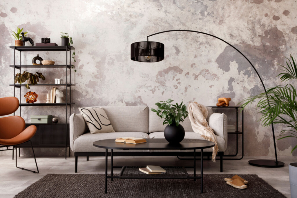 Interior de uma sala de estar com sofá cinza de design, poltrona, mesa de centro preta, abajur e elegantes acessórios pessoais