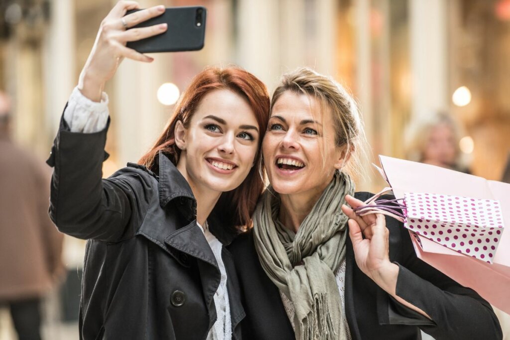 Duas mulheres em um shopping sorrindo e tirando foto 