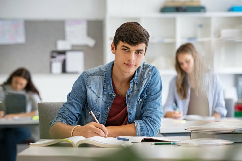 Jovem sentado em sala de aula estudando