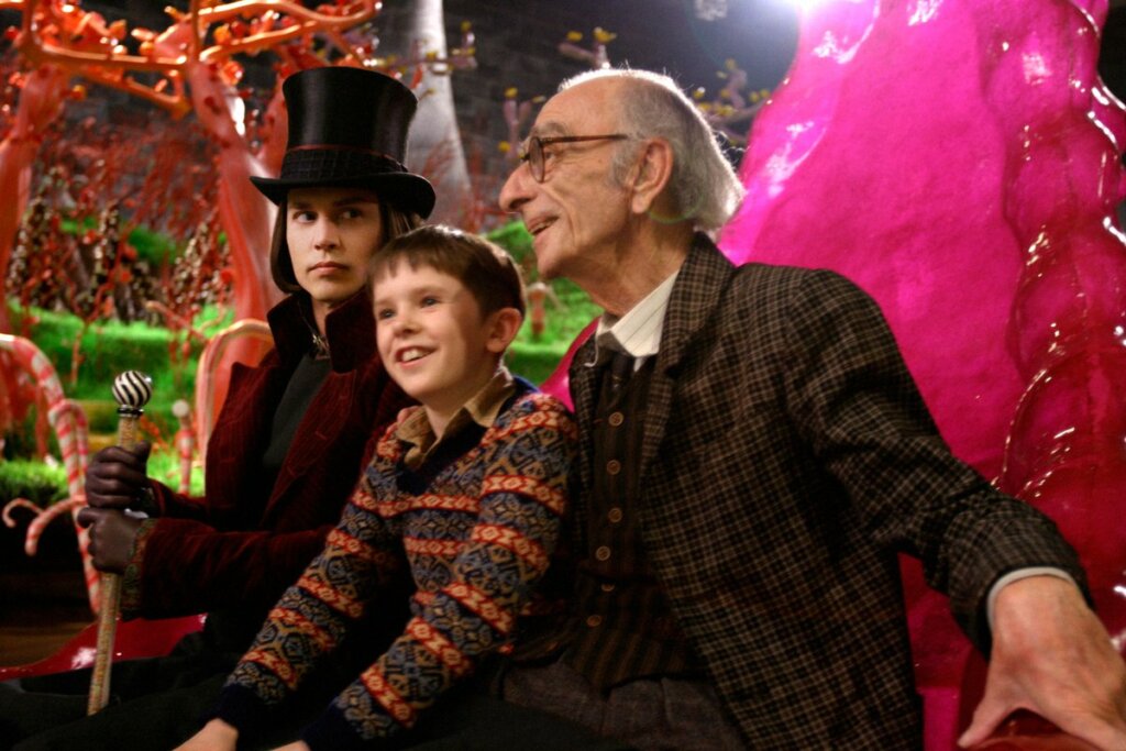 Cena do filme "A fantástica fábrica de chocolate"; menino, avô e Willy Wonka