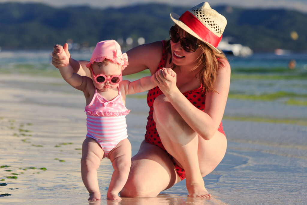 Mãe e bebê sorrindo na praia