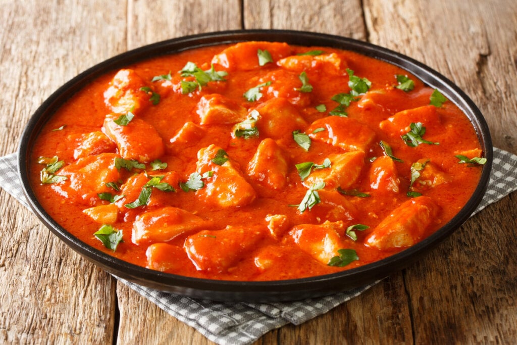 Panela preta com frango com molho de tomate polvilhado com coentro picado