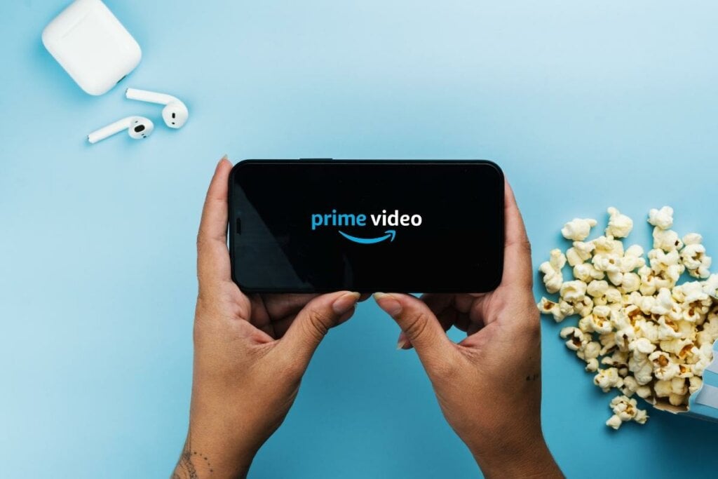 Mãos segurando um celular com o logotipo do Prime Video