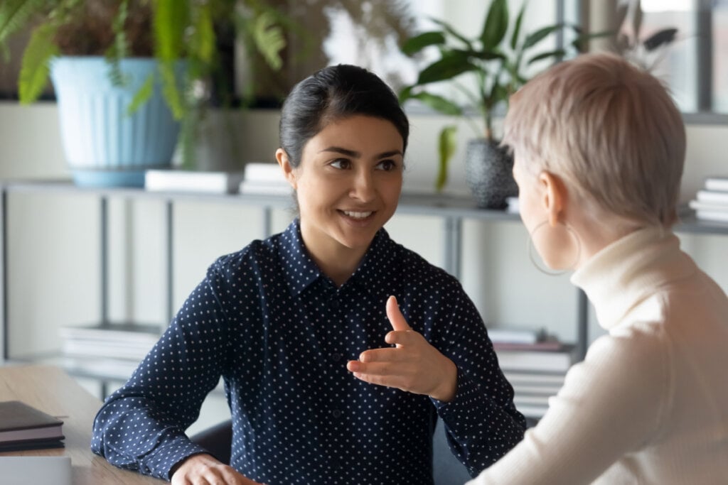 Mulheres sentadas uma de frente para outra conversando