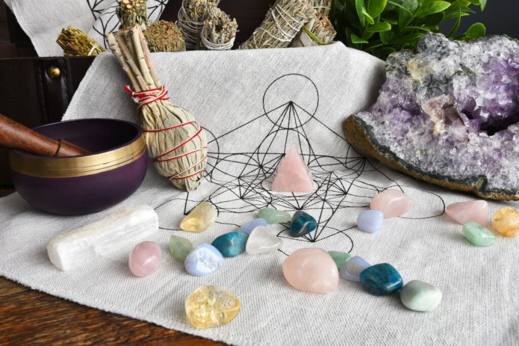 Pedras coloridas em cima de pano branco e outros itens de astrologia ao fundo