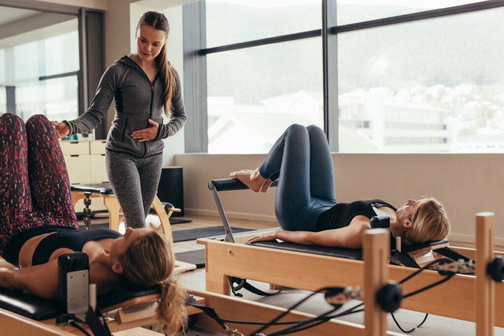 Professora de pilates ajudando duas mulheres com os exercícios