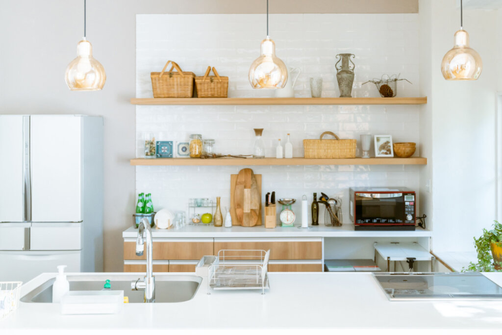 Ambiente de cozinha claro, com objetos organizados em bancada e prateleiras