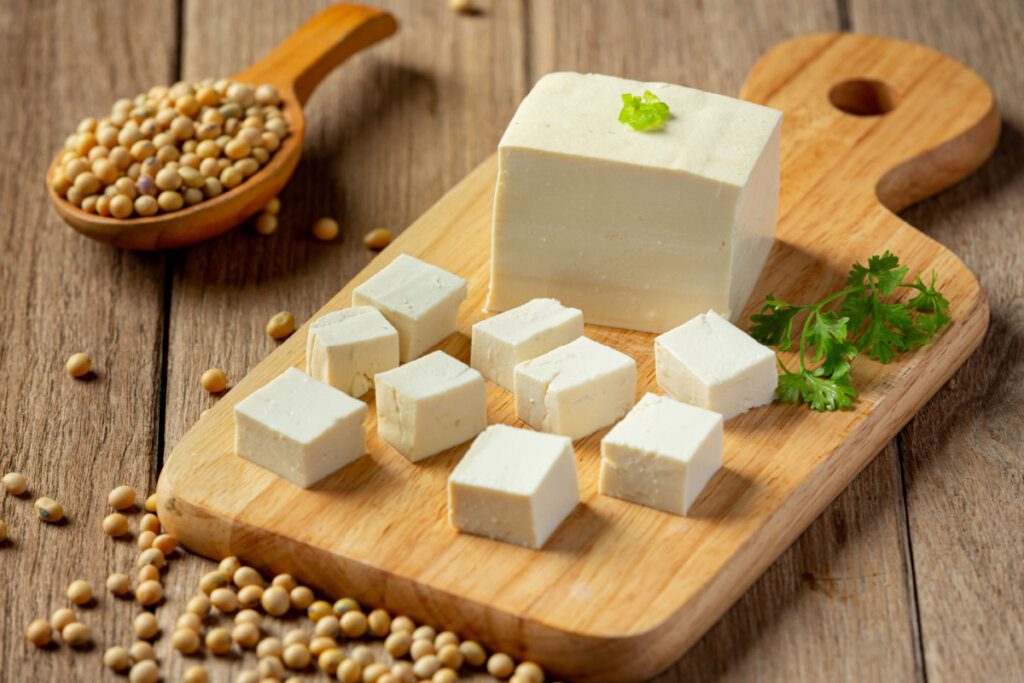 Tofu cortado em tábua de madeira com grãos de soja em volta
