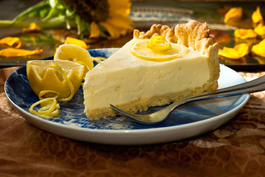 Pedaço de torta de limão em cima d eum prato branco e azul