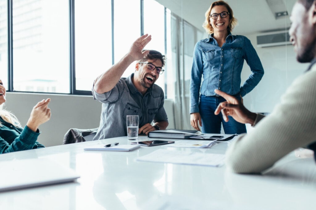 Colaboradores sorridentes em uma sala de reunião