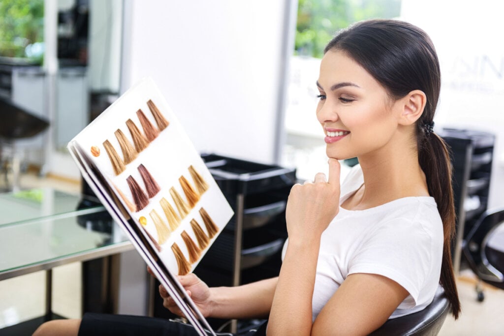 Cliente em salão de beleza segurando amostras de coloração de cabelo