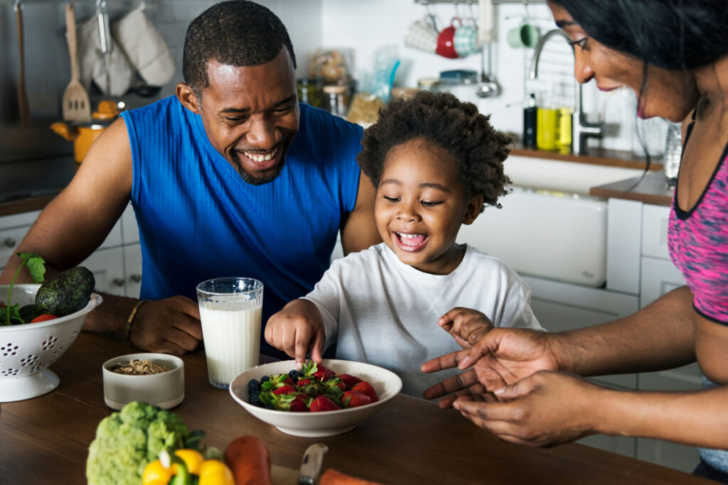 Pais incentivando criança a comer alimentos saudáveis