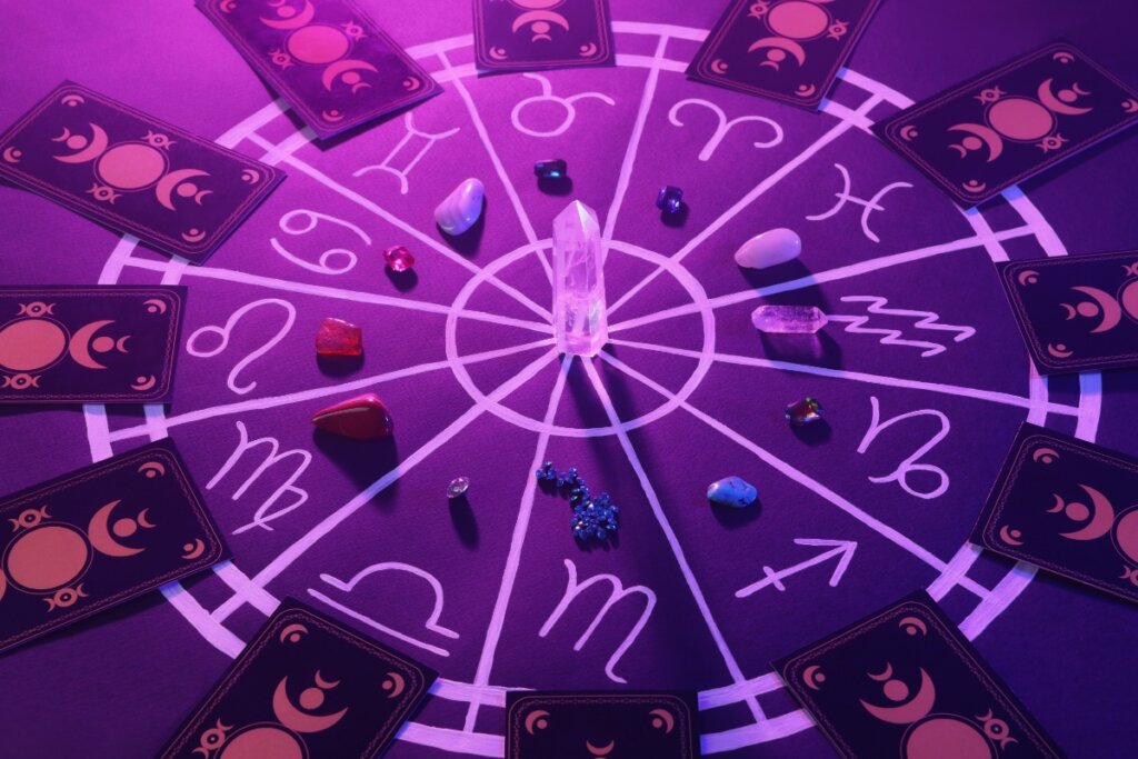 Ilustração dos doze signos do zodíaco em uma mesa roxa com cristais e cartas de tarô