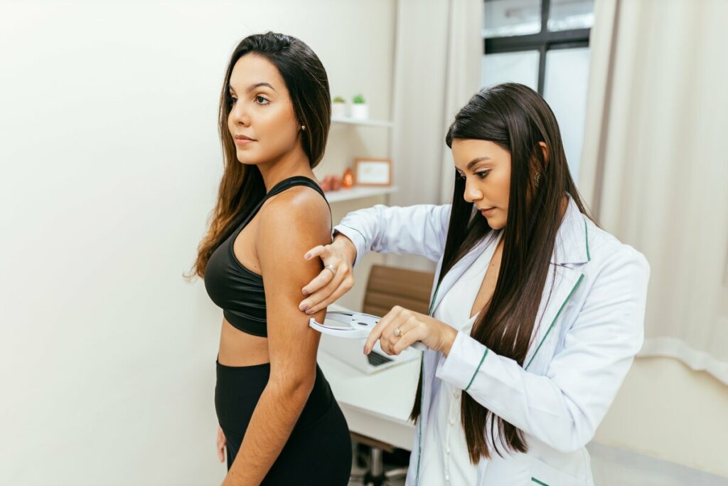 Mulher em pé com médica examinando o seu braço