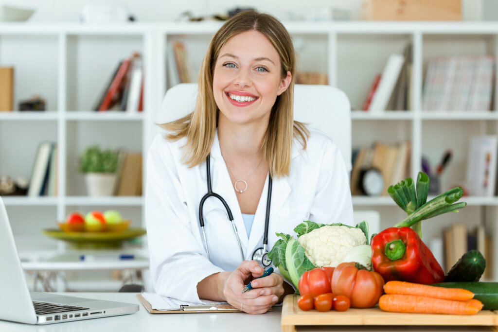 Médica sentada em frente a uma mesa com legumes