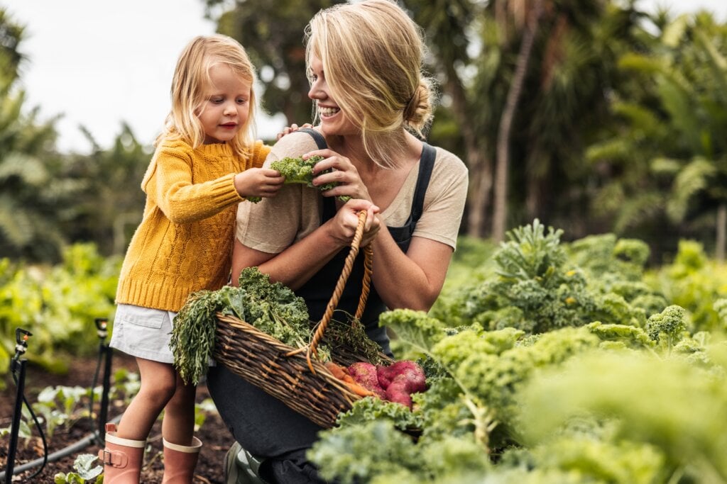 Mãe e filha colhendo plantações da horta caseira