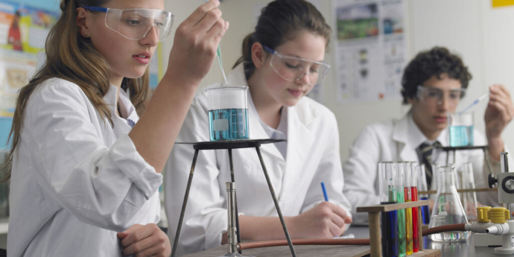 Estudantes adolescentes realizando experimentos no laboratório em aula de química