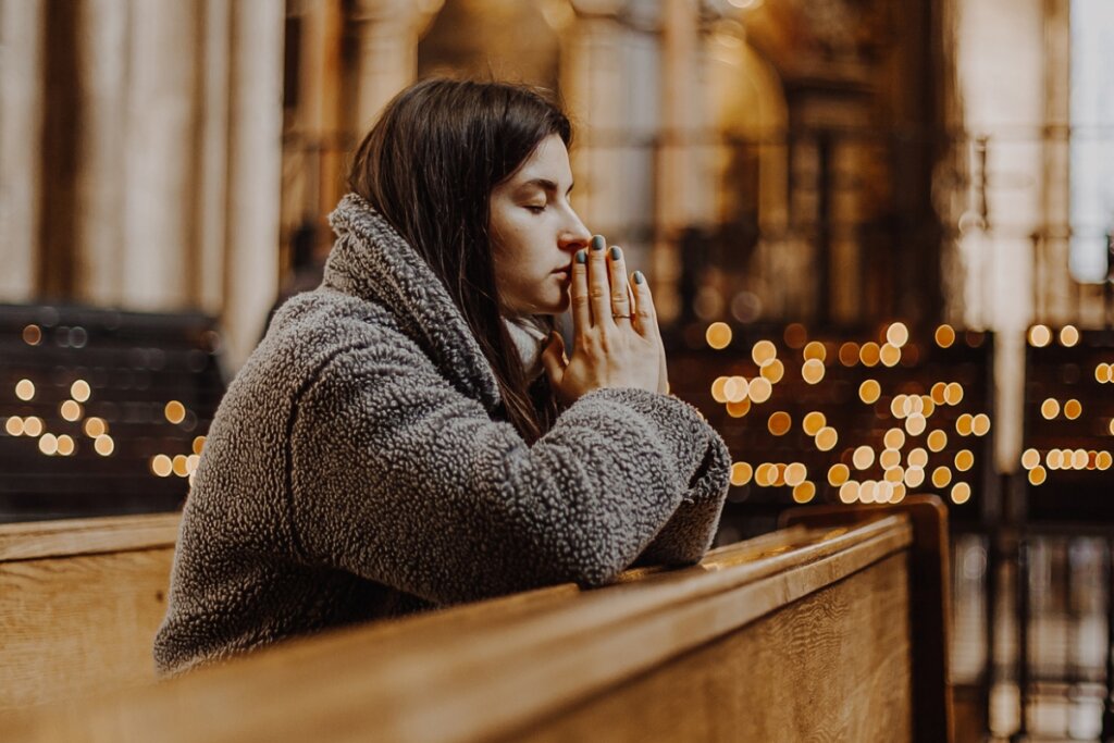 Mulher ajoelhada em uma igreja orando 