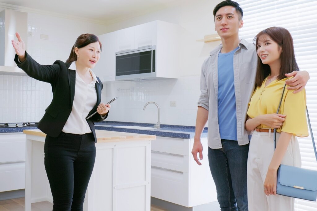 Homem e duas mulheres olhando a cozinha de uma casa 