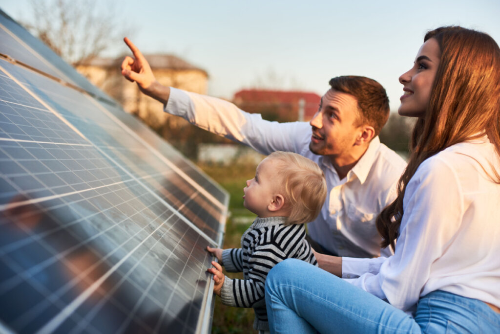 Homem mostra à família os painéis solares no terreno perto da casa 