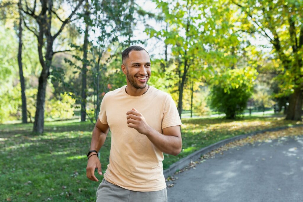 Homem vestindo blusa amarela e bermuda cinza correndo em um parque