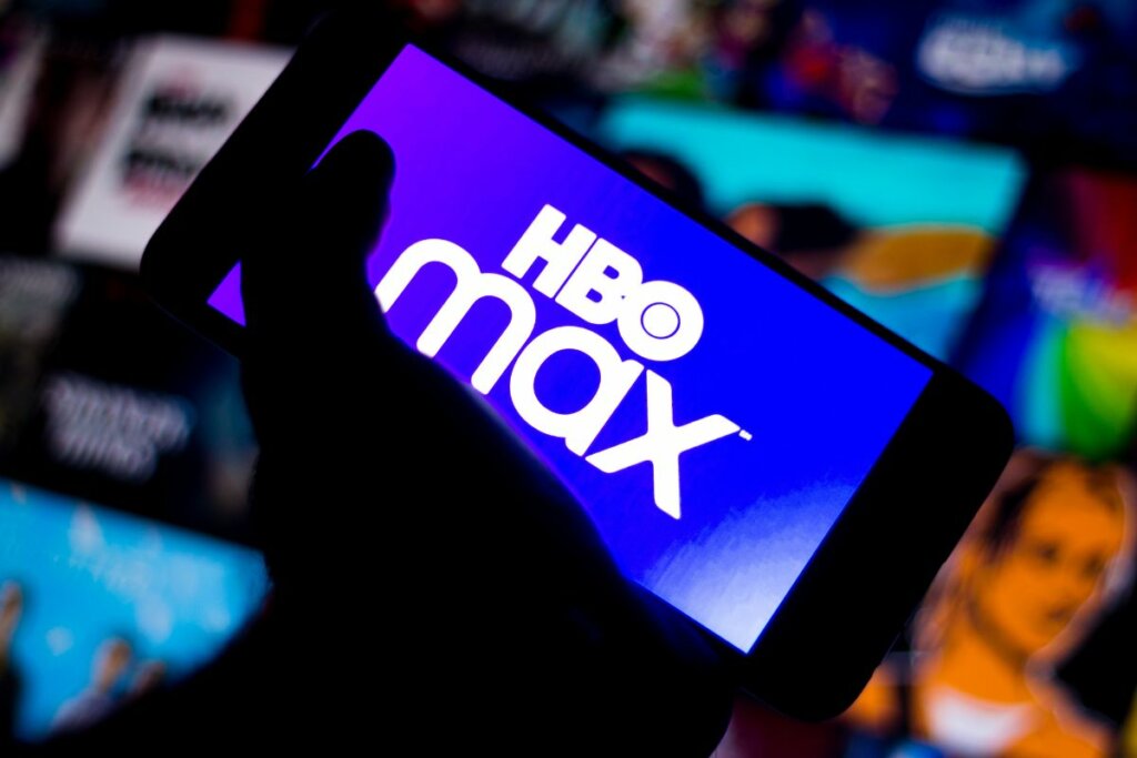 Logo da HBO Max na tela de um celular com uma mão segurando