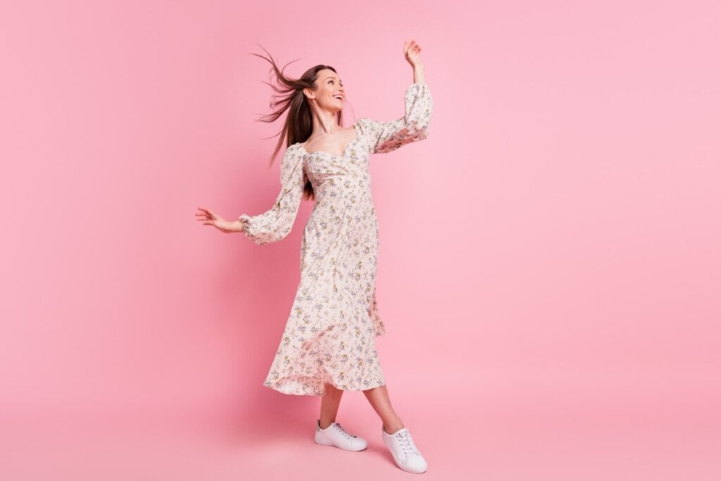 Mulher com vestido florido em frente a um fundo rosa