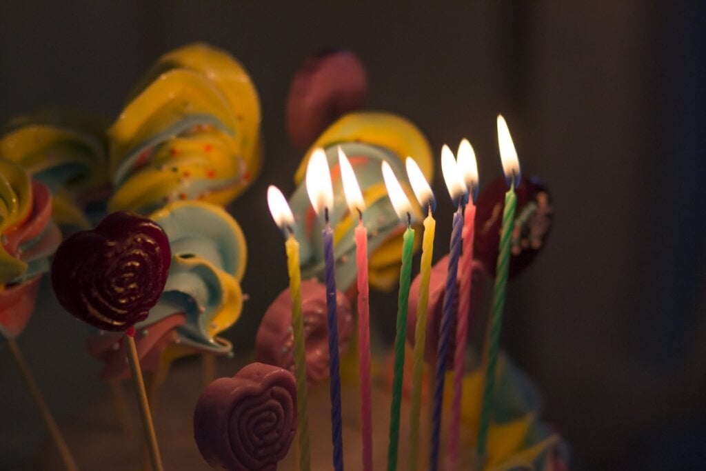 Velas coloridas acesas em cima de um bolo 