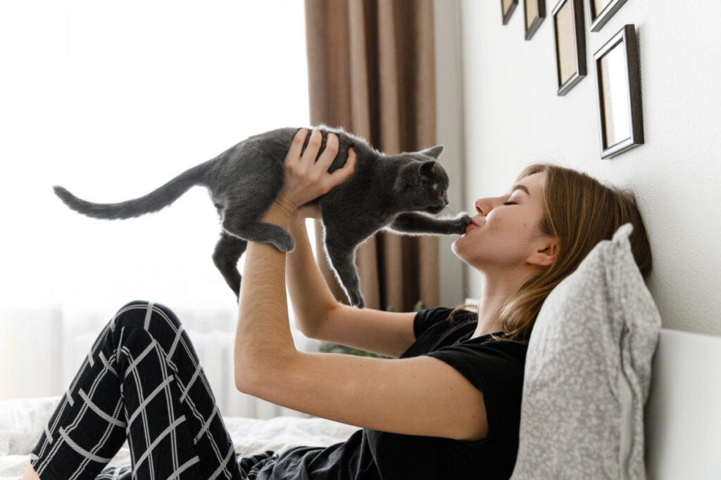 Garota de pijama segurando um gato preto nos braços