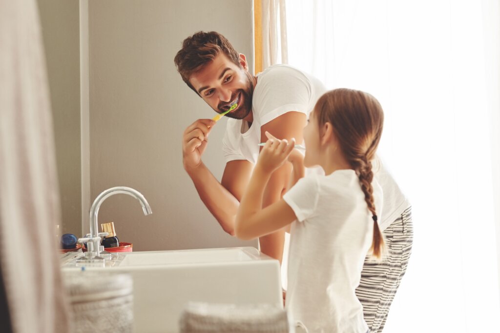 Pai e filha escovando os dentes