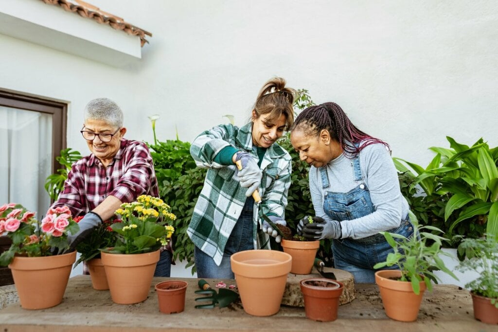 Três mulher cuidando de flores em vasos de planta