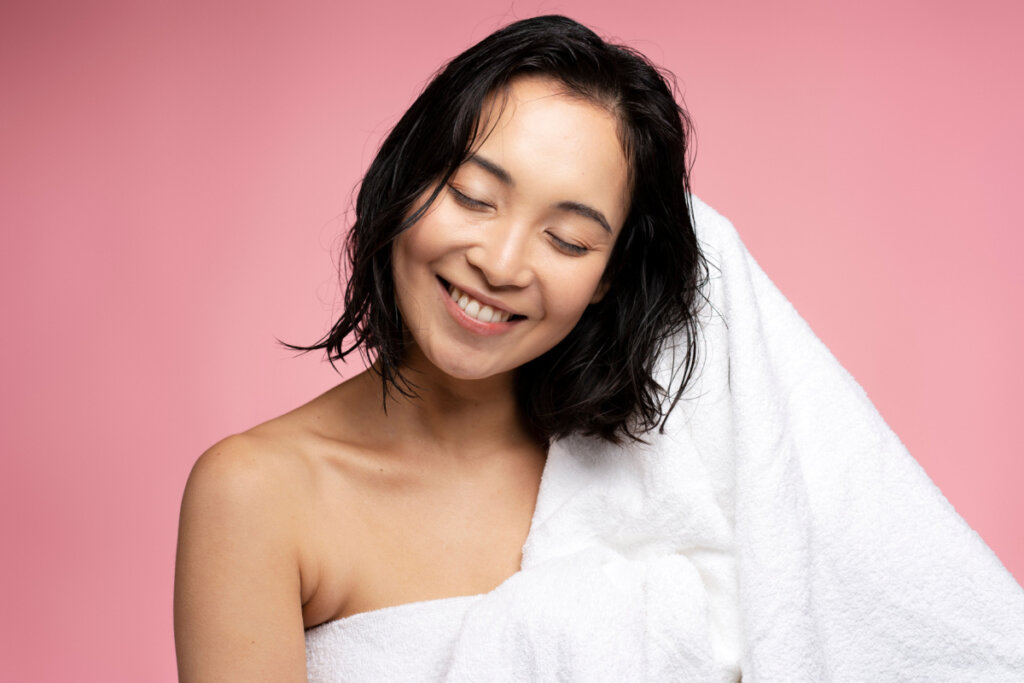 Mulher sorrindo secando o cabelo com toalha