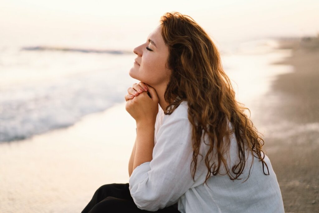Mulher sentada em uma praia orando