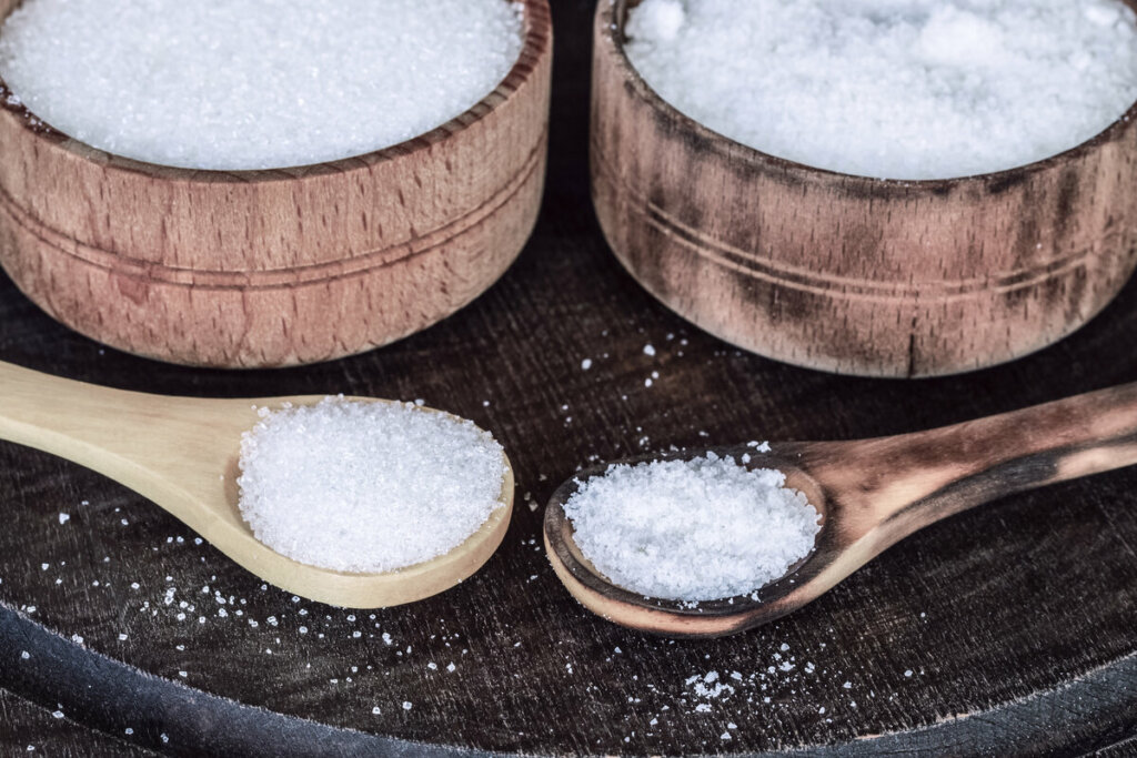 Recipientes e colheres de madeira com sal e açúcar
