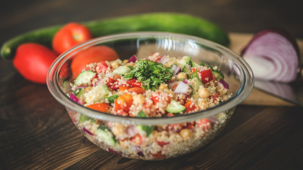 Salada de quinoa com grão-de-bico, tomate e pepino em recipiente transparente