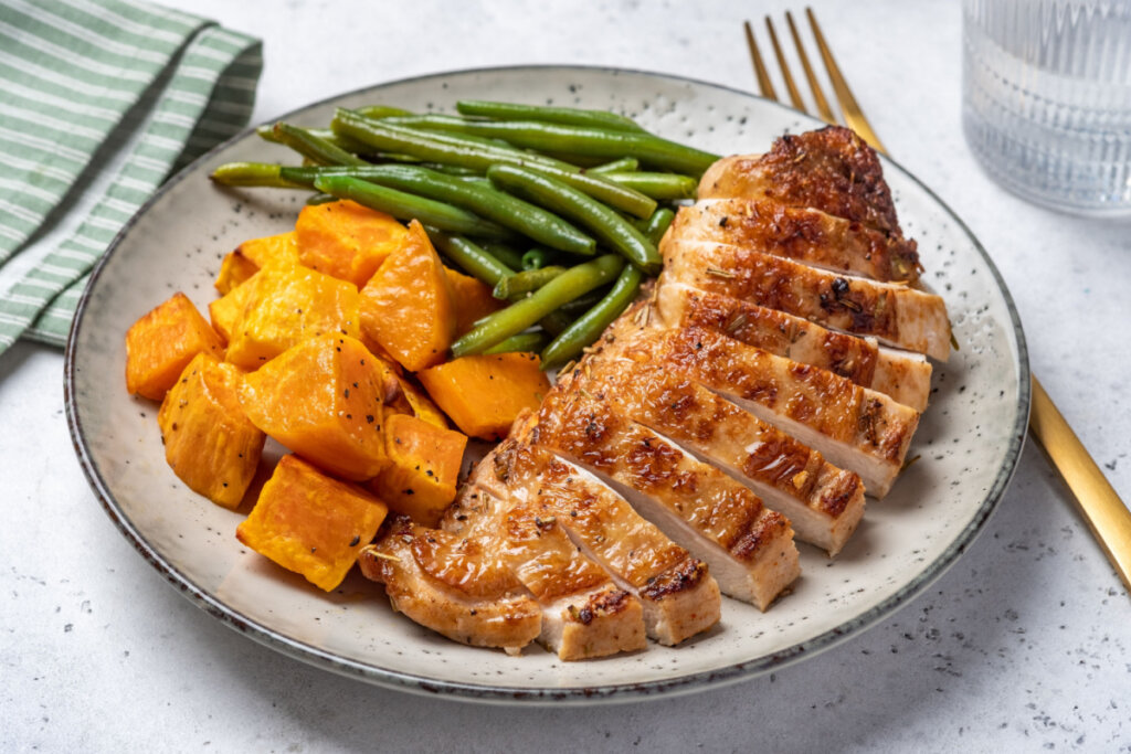 Frango assado com batata-doce laranja e salada de vagem em prato