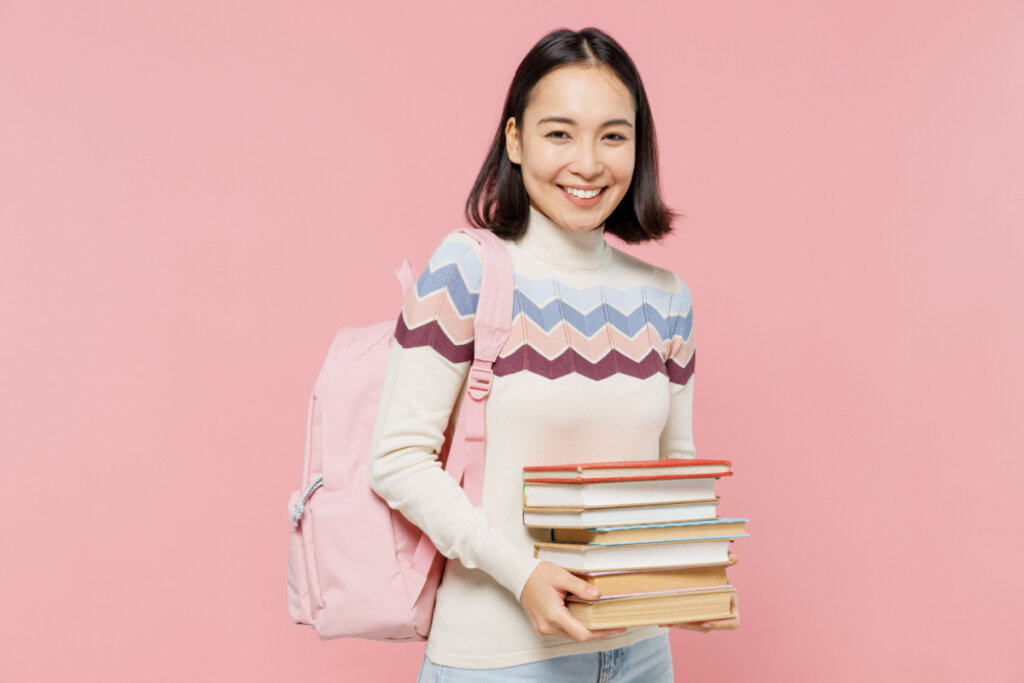 Garota adolescente segurando livros e com mochila no ombro