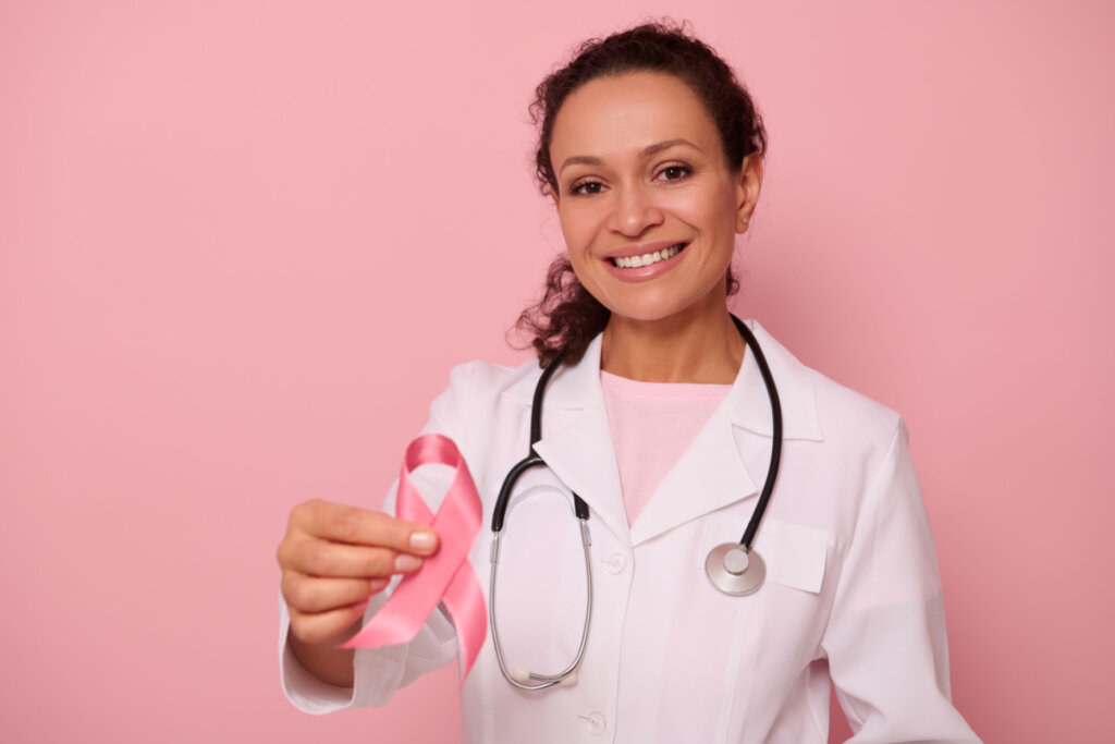 Médica segurando laço rosa, símbolo da campanha contra o câncer de mama