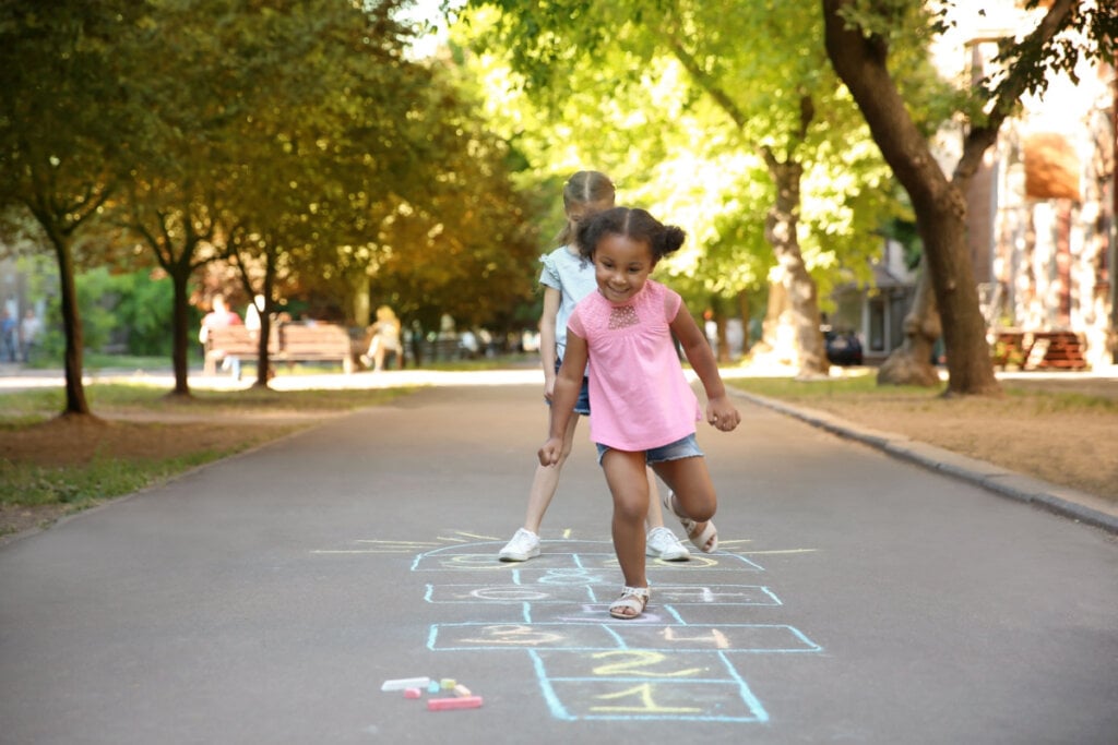 Duas meninas na rua brincando de amarelinha