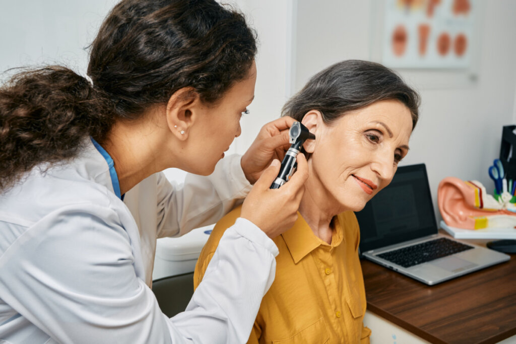 Médica examinando ouvido de paciente com aparelho