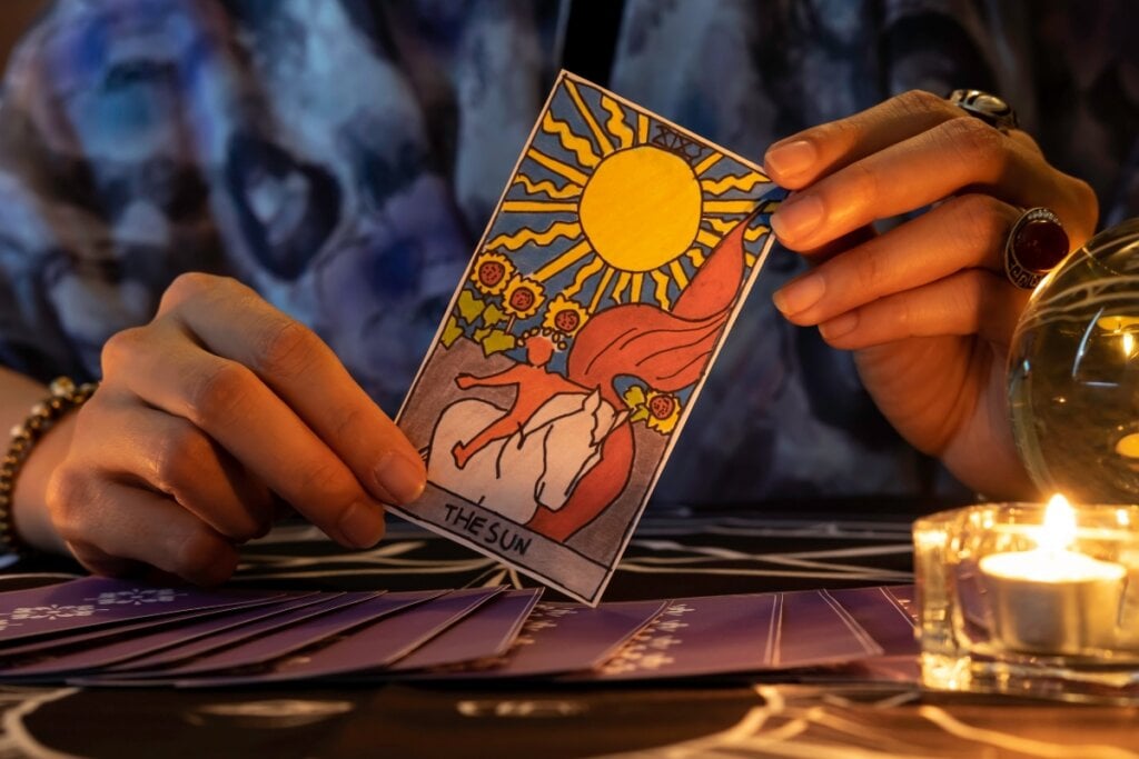 Mãos feminina segurando uma carta de tarot