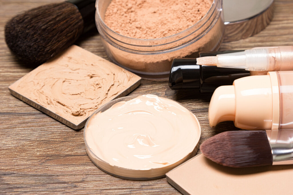 Diferentes produtos de maquiagem como base, corretivo, pó e pincéis.