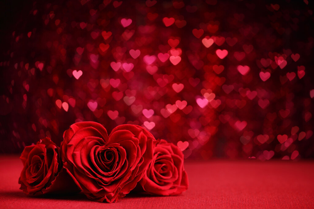 Rosas-vermelhas em formato de coração e com corações brilhantes ao fundo