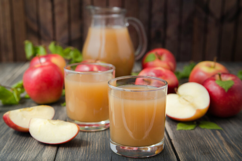 Dois copos com suco de maçã em cima de uma mesa de madeira