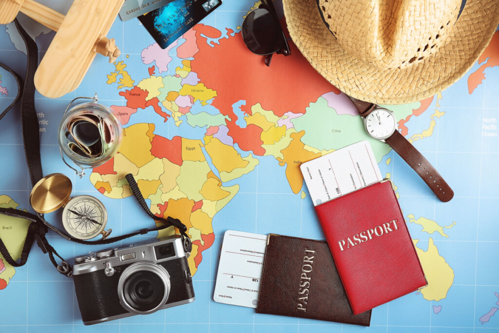 Imagem com elementos relacionados a viagem, como passaporte, chapéu, relógio, máquina fotográfica etc.