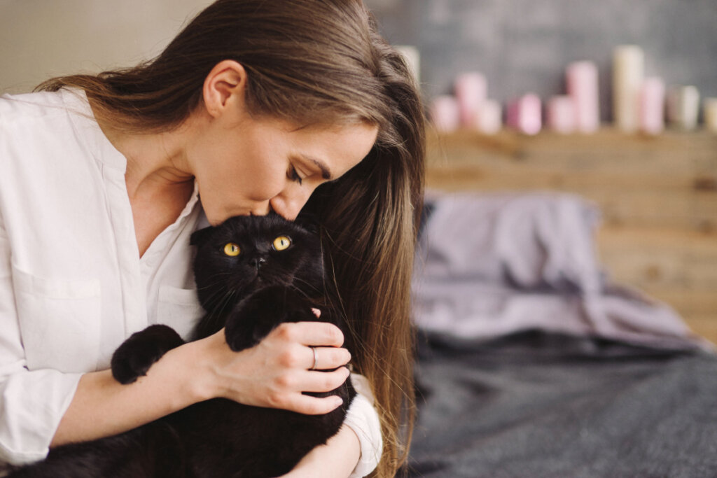 Mulher dando um beijo na cabeça de um gato preto