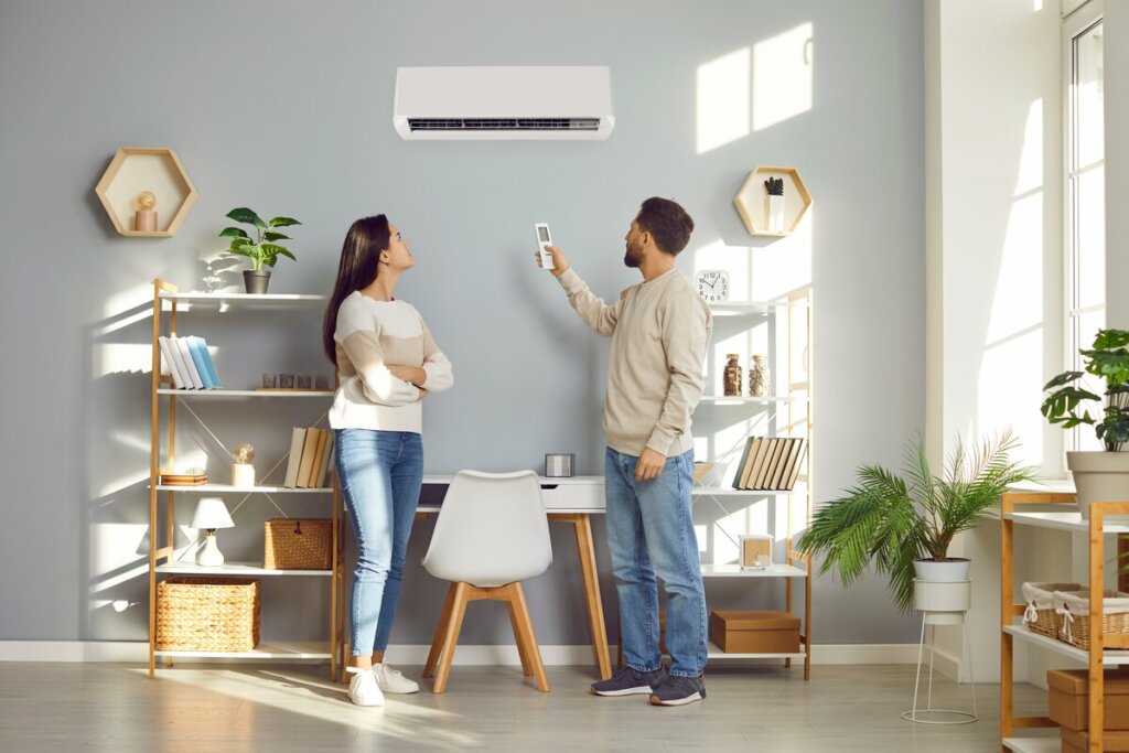 Homem e mulher em pé em uma sala de estar olhando para um ar-condicionado
