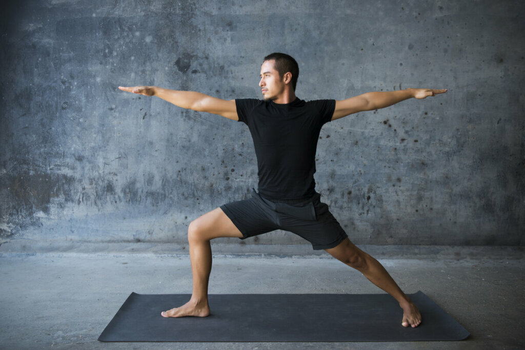 Homem em cima de um tapete cinza fazendo ioga