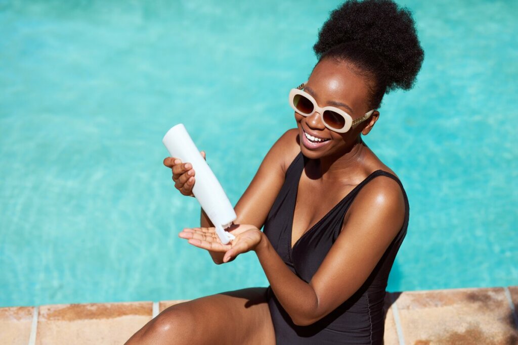 Mulher passando protetor solar na beira de uma piscina