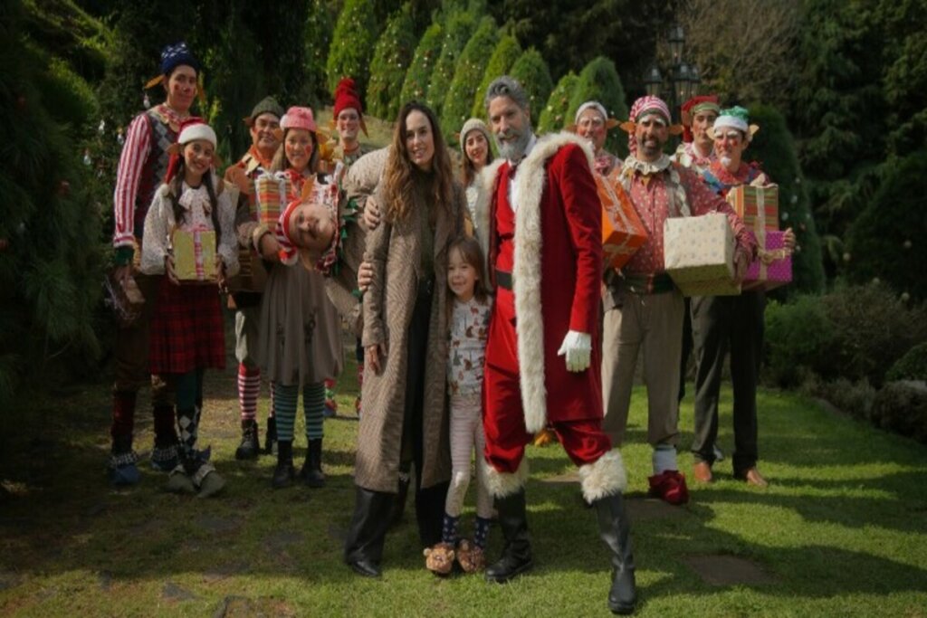 Cena do filme Dating Santa com diversos personagens natalinos em meio a árvores 